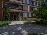 a residential driveway with a bench and bushes in between buildings and green grass on either side