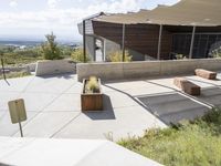 the outdoor area has two benches next to a concrete building with a large awning over it