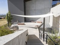 the outdoor area has two benches next to a concrete building with a large awning over it