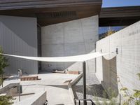 the outdoor area has two benches next to a concrete building with a large awning over it