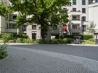 a courtyard with benches, trees, and several apartment blocks on one of the sides