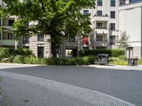 a courtyard with benches, trees, and several apartment blocks on one of the sides