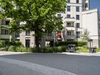 a courtyard with benches, trees, and several apartment blocks on one of the sides