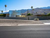 a residential building in the desert with palm trees on it and mountains in the distance