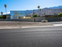 a residential building in the desert with palm trees on it and mountains in the distance