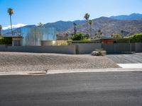 a residential building in the desert with palm trees on it and mountains in the distance