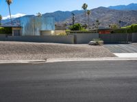 a residential building in the desert with palm trees on it and mountains in the distance