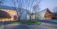 several metal trees are in the courtyard near some glass windows and a building at night