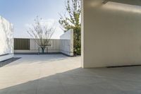 a modern looking apartment patio with white walls and large trees in a courtyard outside the house