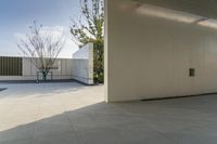 a modern looking apartment patio with white walls and large trees in a courtyard outside the house