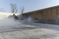 there is some steam in the courtyard of this building next to trees and grass near the wall