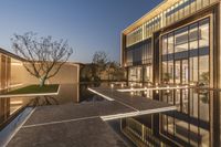 an outdoor view of the building in front of the pool at dusk with lights on