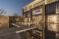 an outdoor view of the building in front of the pool at dusk with lights on