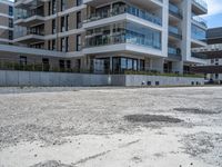 an empty parking lot outside an apartment complex with concrete floors and a balcony on top