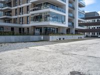 an empty parking lot outside an apartment complex with concrete floors and a balcony on top