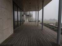 wooden flooring and pillars in the corner of a large building, with fog on the glass windows