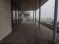 wooden flooring and pillars in the corner of a large building, with fog on the glass windows