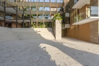 concrete and brick patio at the edge of a building with palm trees behind it and stairs leading to the second floor