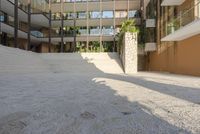 concrete and brick patio at the edge of a building with palm trees behind it and stairs leading to the second floor