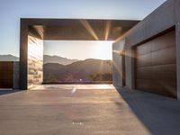 a sun shines over the mountains and entrance to an outdoor garage building, with wooden doors