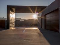 a sun shines over the mountains and entrance to an outdoor garage building, with wooden doors