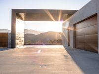 a sun shines over the mountains and entrance to an outdoor garage building, with wooden doors