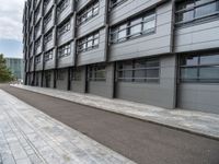 an empty, side view of a street that is next to a building with glass doors