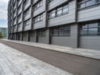 an empty, side view of a street that is next to a building with glass doors