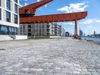 this red and orange crane is in a building complex with a river view in the background