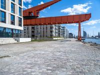 this red and orange crane is in a building complex with a river view in the background