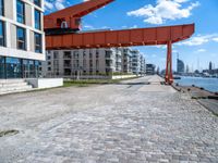 this red and orange crane is in a building complex with a river view in the background