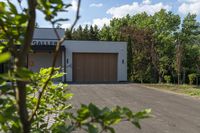 garage in a wooded area with a brown door and white exterior with red letters saying gallery