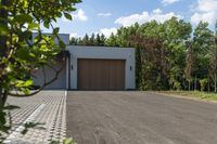 garage in a wooded area with a brown door and white exterior with red letters saying gallery