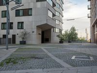 an empty walkway and small planters along a street between buildings and trees in the background