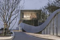 the tree is growing and beside the building are stairs with sculptures of birds walking on them