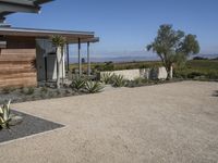 this home has concrete driveways and gravel patios to provide space for plants, bushes, and trees