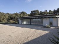 a house that has gravel flooring around it outside, with an open garage and a grassy lawn in front