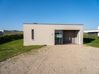 a tiny house is situated on a grassy hill, near the ocean, and with a private garage that sits in the grass