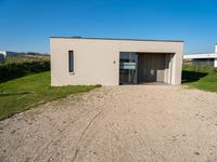 a tiny house is situated on a grassy hill, near the ocean, and with a private garage that sits in the grass