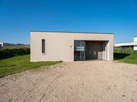 a tiny house is situated on a grassy hill, near the ocean, and with a private garage that sits in the grass