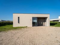 a tiny house is situated on a grassy hill, near the ocean, and with a private garage that sits in the grass