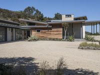 the entrance to a home with wooden siding and gravel parking lot in front of it