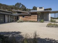 the entrance to a home with wooden siding and gravel parking lot in front of it