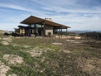 a home is on a hillside overlooking a field and the mountains in the background for a story