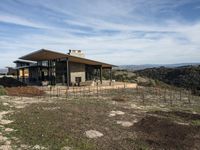 a home is on a hillside overlooking a field and the mountains in the background for a story