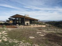 a home is on a hillside overlooking a field and the mountains in the background for a story