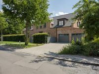 the brick and stone frontage of the home shows that there is a paved driveway in front of it