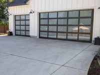 a building with glass garage doors and large window panels in the front of it is in a driveway