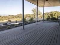 the covered deck area with the view to the outdoors area of the house and forest in the distance