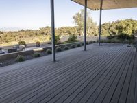 the covered deck area with the view to the outdoors area of the house and forest in the distance